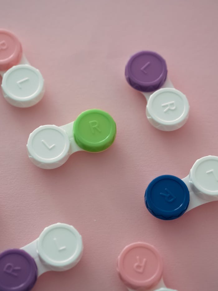 Aesthetic arrangement of colorful contact lens cases on a soft pink background.